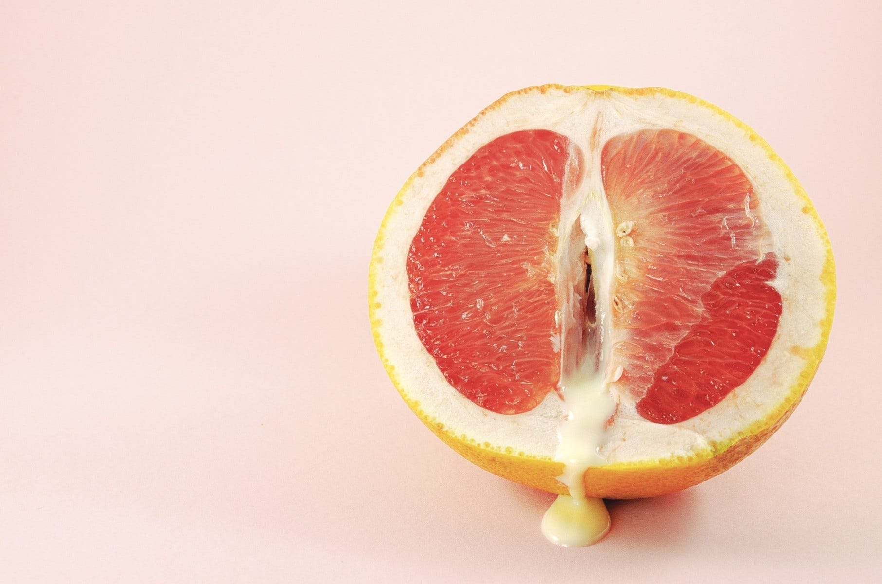 A grapefruit cut in half with juice coming out of is, symbolism female ejaculation from g-spot stimulation